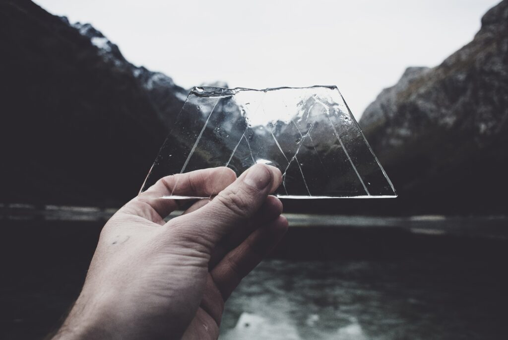 Hand holding up glass in front of a mountain - how to motivate and engage employees with transparency